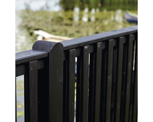 Detaljvy av ett svart trästaket framför en damm