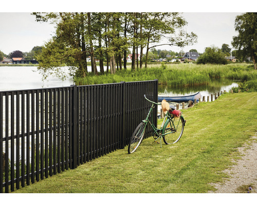 Mörkbrunt trädgårdsstaket i trä bredvid en sjö med en cykel