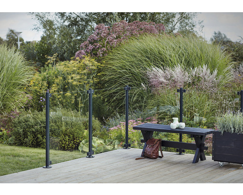 Terrass med glasräcke, bänk och växter i trädgården