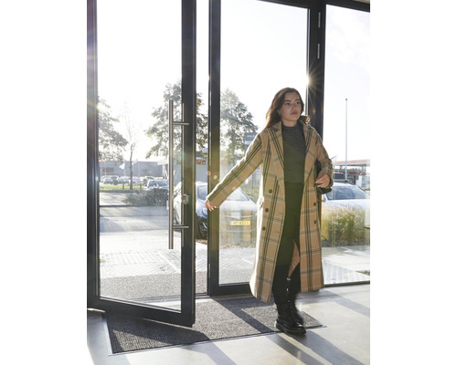 Entré med dörrmatta och en kvinna som öppnar en dörr