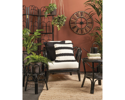 Vardagsrum med rottingfåtölj, sidobord, rumsavdelare, väggklocka och krukväxter för en mysig atmosfär