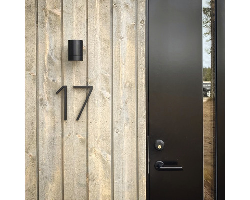 Exteriör av ett hus med trävägg, husnummer 17, utomhuslampa och ytterdörr