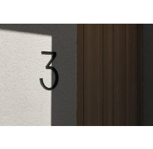 Husnummer tre av metall på en vägg