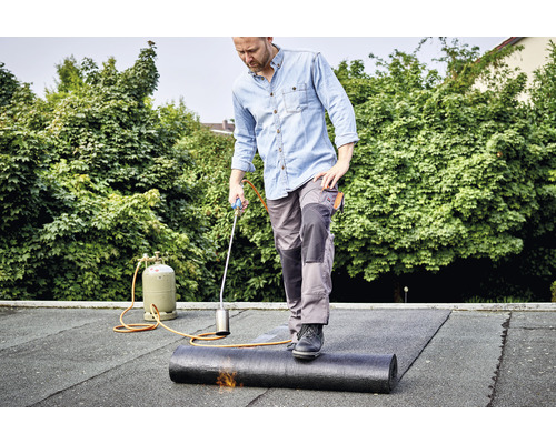 Man lägger ett takmembran på ett tak med en takbrännare.