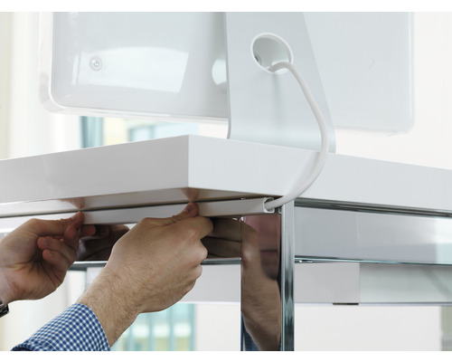 Person fäster en kabelkanal på ett skrivbord för kabelhantering.