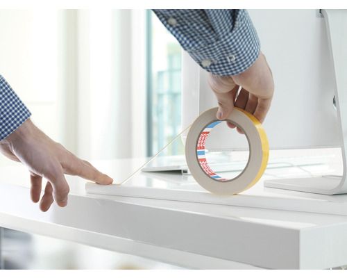 Dubbelhäftande tejp appliceras på en vit yta.