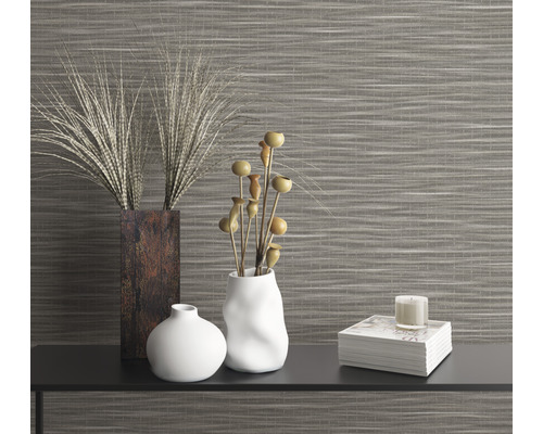 Dekorativt arrangemang med vaser, växter och ljus framför en väggbeklädnad