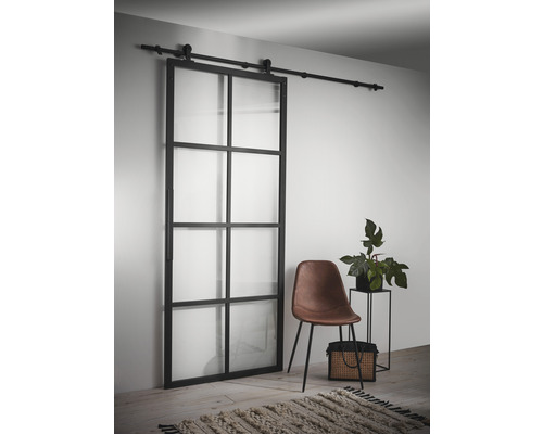 Skjutdörr med stålram och glaspaneler i interiör med stol och växt