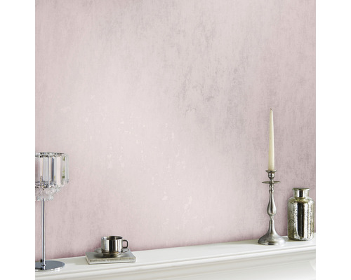 Rosa tapet med ljusstake, vas och tekopp på en spiselkrans