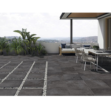 Terrass med mörka stengolv, sittgrupp och palmer