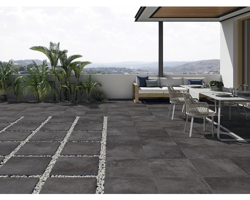 Terrass med mörka stengolv, sittgrupp och palmer