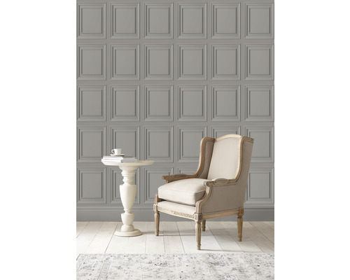 Scen med en väggbeklädnad med kassettmönster, en fåtölj och ett sidobord.