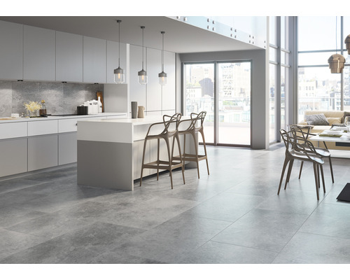 Ljust vardagsrum med gråa golvplattor, köksö och sittplatser