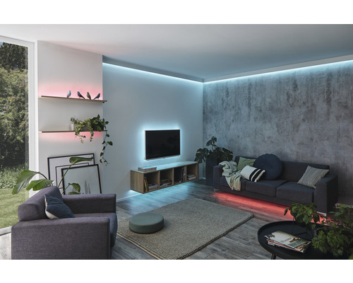 Vardagsrum med soffa, fåtölj, hyllor och indirekt belysning