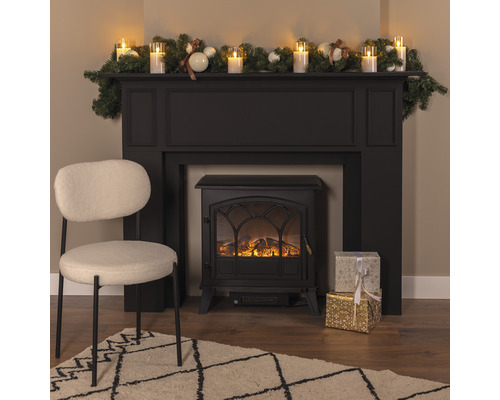 Dekorativ interiör med elektrisk eldstad, stol, matta och juldekoration