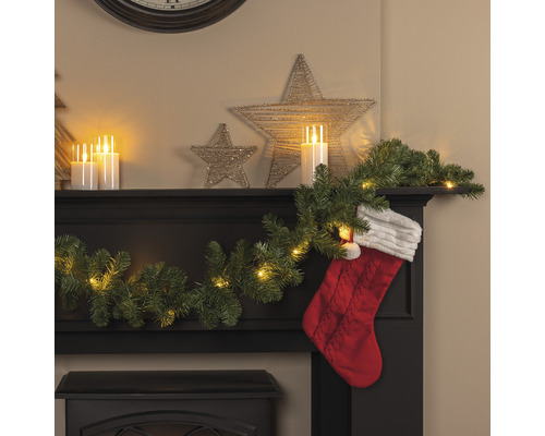 Dekorativ öppen spis med LED-ljusslinga, girlang av gran, stjärnor och julstrumpa för en festlig atmosfär