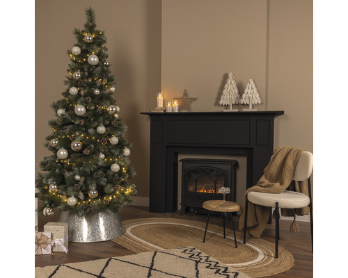 Juldekorerat vardagsrum med julgran, öppen spis och matta