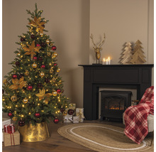 Dekorerad julgran i ett vardagsrum med öppen spis och presenter.