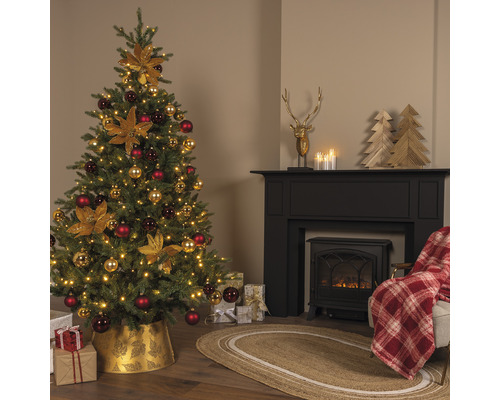 Festligt dekorerad julgran bredvid en öppen spis med dekorationer och presenter