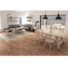 Vardagsrum med träbord, stolar, soffa, matta och eldstad på terrakotta klinker