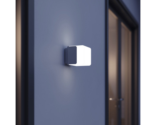 Fyrkantig vägglampa på en vägg bredvid en dörr