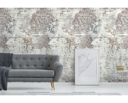 Vardagsrum med grå soffa framför en tapet som imiterar en smulande tegelvägg.