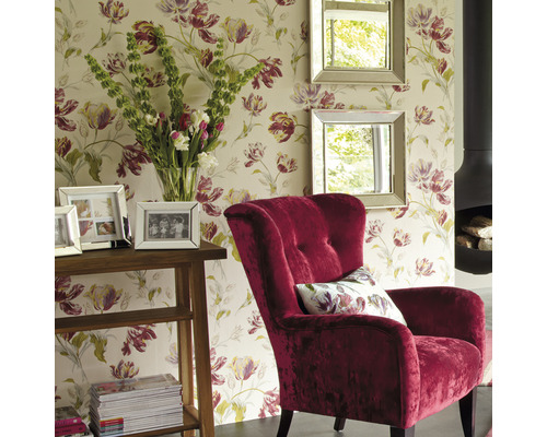Vardagsrum med blommig tapet, fåtölj, speglar, bord och öppen spis