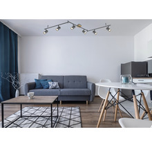 Vardagsrum med soffa, bord, stol och taklampa med sex spotlights
