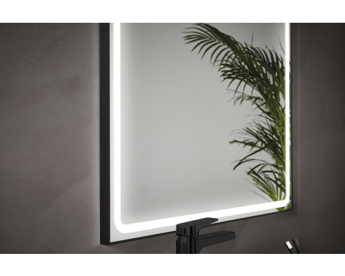 Belyst badrumsspegel med beröringssensor bredvid ett handfat