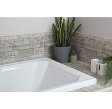 Badrumsscen med vitt badkar, väggpaneler med träutseende och dekorativa växter