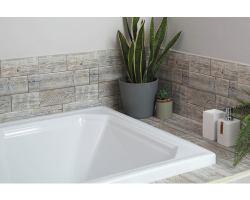 Badrumsscen med vitt badkar, väggpaneler med träutseende och dekorativa växter