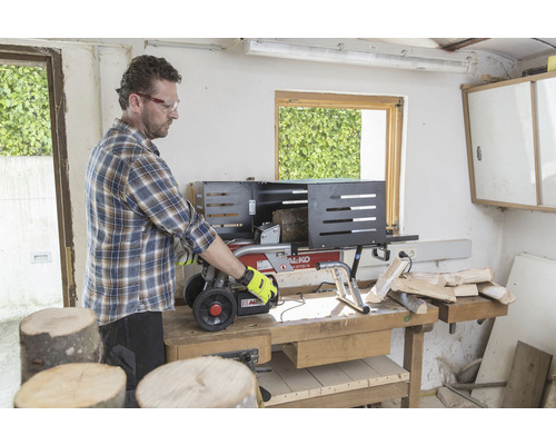 En man använder en vedklyv på en arbetsbänk för att klyva ved.