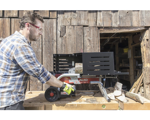 En man använder en AL-KO vedklyv framför en trävägg.