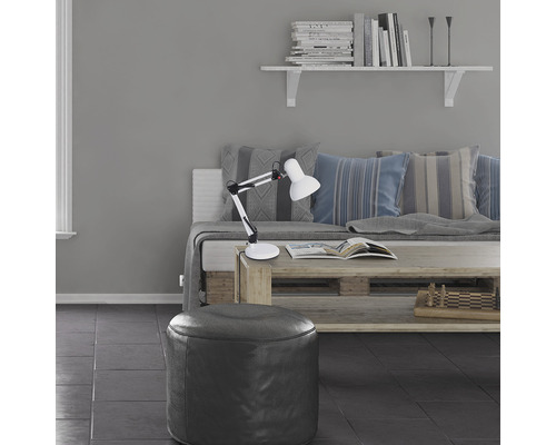 Vardagsrum med svängarmslampa, ottoman, bokhylla och soffa