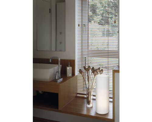 Modernt badrum med tvättställ, armatur, spegel, lampa och fönsterjalusier.