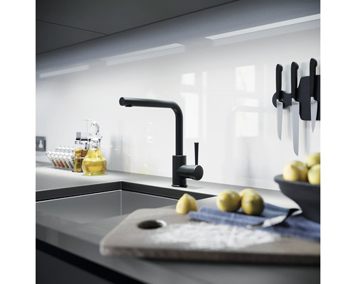 Modernt kök med svart kran, diskho och köksredskap