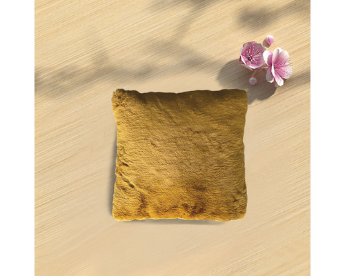 Fyrkantig prydnadskudde med pälstextur på en träyta