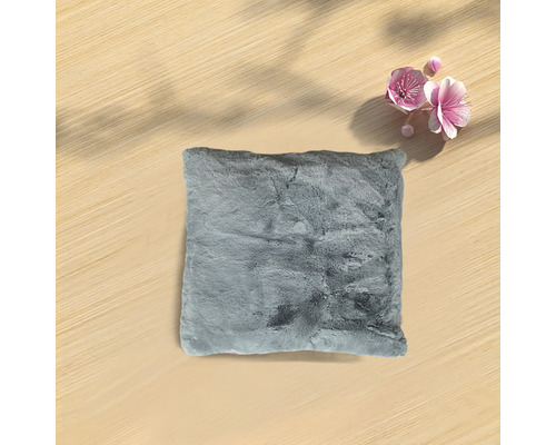 Grå prydnadskudde med pälsstruktur på ett träbord