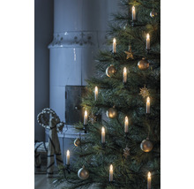 Julgran med ljus och ornament, öppen spis i bakgrunden