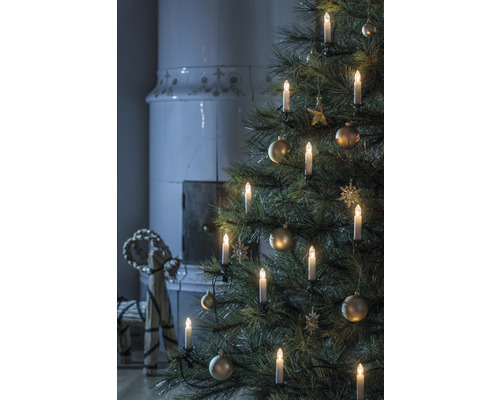 Julgran med ljus och ornament, öppen spis i bakgrunden