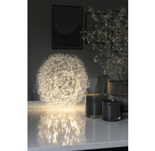 Dekorativ bordslampa i klotform med metalltrådsnät och LED-lampor på ett bord