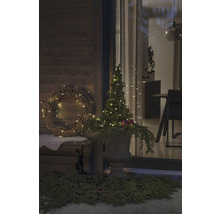 Dekorerad veranda med krans, upplyst träd och planteringskärl