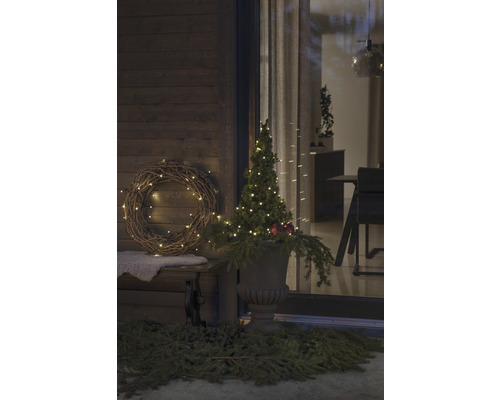 Dekorerad veranda med krans, upplyst träd och planteringskärl