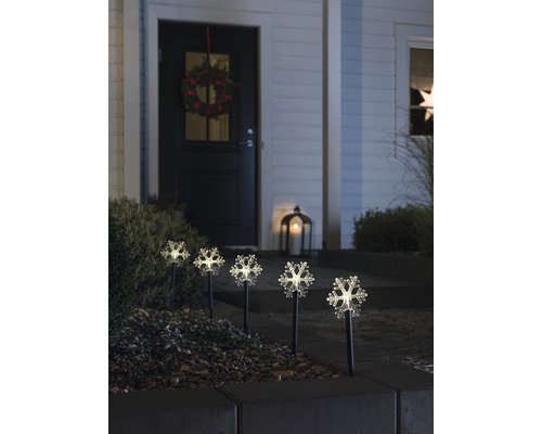 Dekorativa snöflingljus på en husgård med en krans på dörren