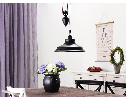Interiörvy med hängande lampa ovanför ett träbord med en vas med blommor