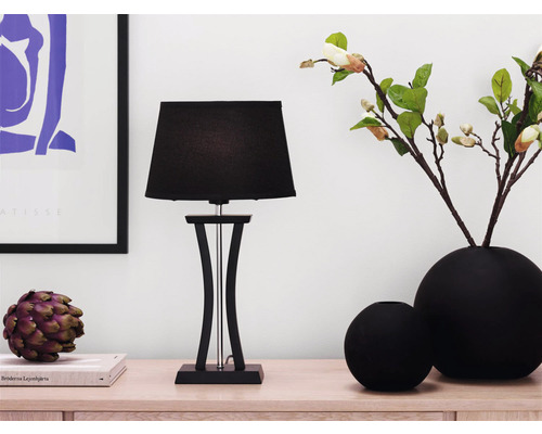 Dekorativ scen med bordslampa, vaser och dekorationsobjekt på en skänk.