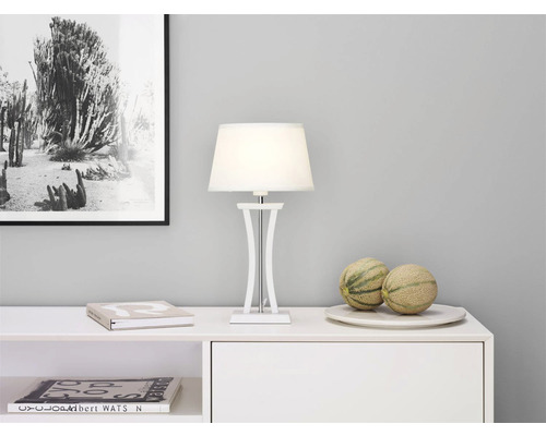 Dekorativ interiör med vit bordslampa, böcker och meloner på en skänk