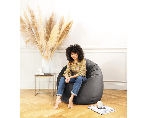 Kvinna sitter i en grå sittsäck i ett ljust rum.