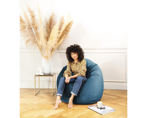 Kvinna sitter i en blå sittsäck i ett ljust vardagsrum
