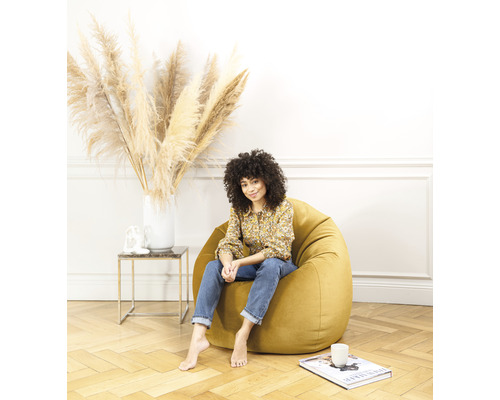 Kvinna sitter på en gul sittsäck i vardagsrummet